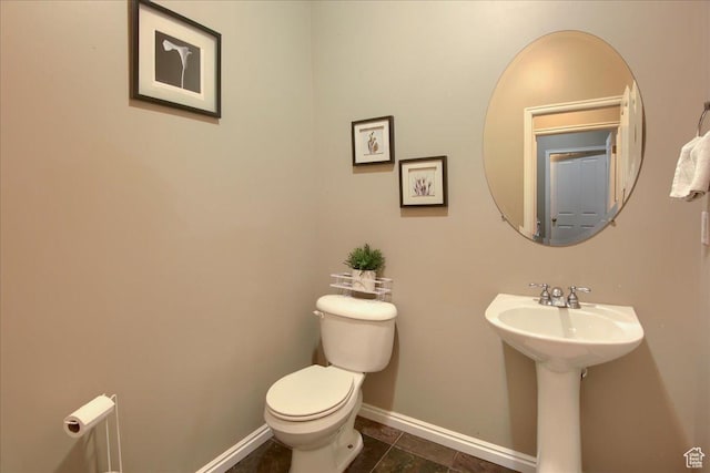 half bathroom with baseboards and toilet