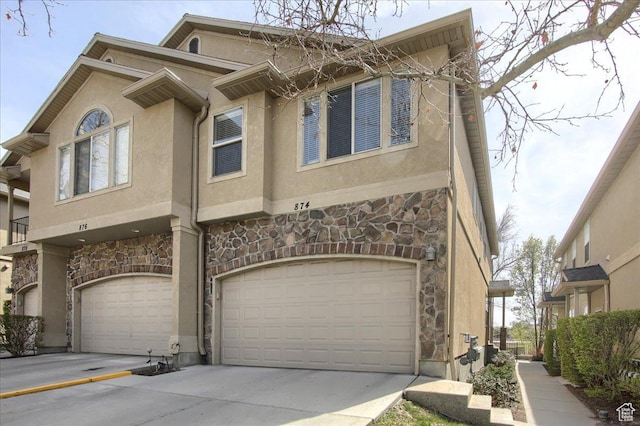townhome / multi-family property featuring driveway, stucco siding, stone siding, and an attached garage