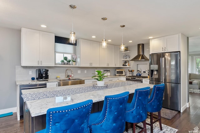 kitchen featuring dark wood-style floors, wall chimney range hood, a sink, stainless steel appliances, and a toaster