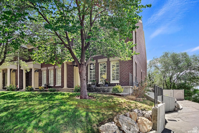 view of front facade featuring a front yard, fence, and brick siding