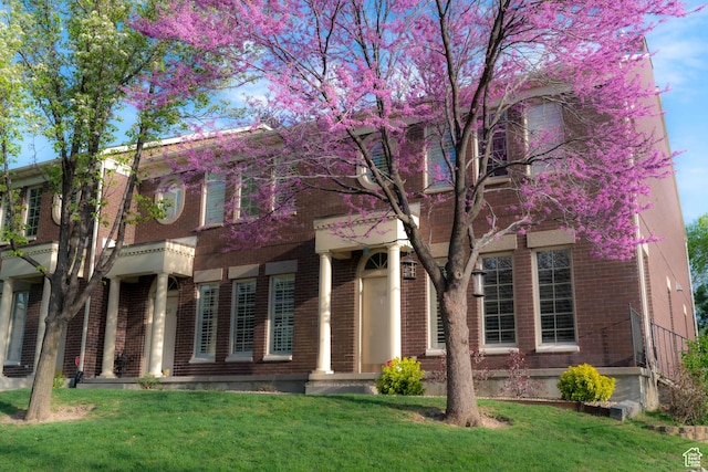 view of front of property featuring a porch, a front yard, and brick siding