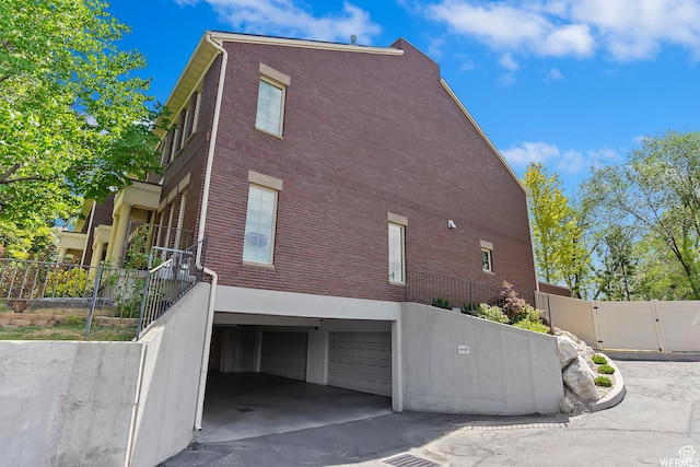 view of side of property featuring an attached garage, fence, and a gate