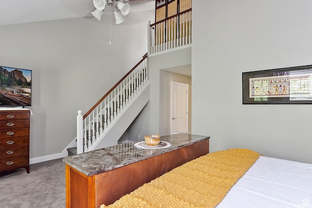 carpeted bedroom featuring ceiling fan, a towering ceiling, and baseboards
