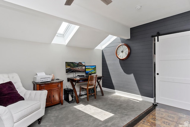 home office featuring wooden walls, vaulted ceiling with skylight, and a barn door