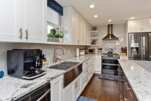kitchen featuring wall chimney exhaust hood, white cabinetry, dark wood-style flooring, a sink, and stainless steel appliances