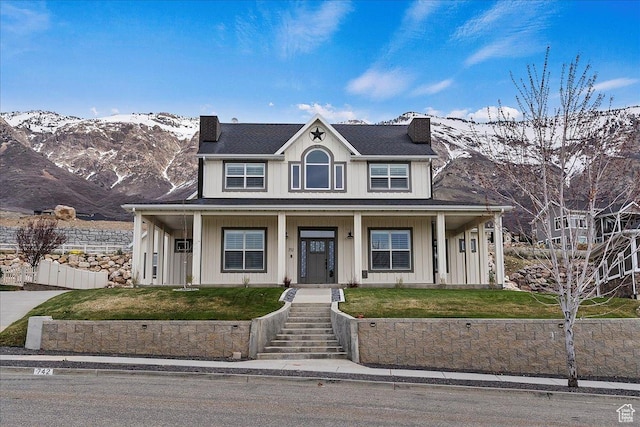 view of front of home featuring a mountain view, covered porch, a chimney, fence, and a front lawn