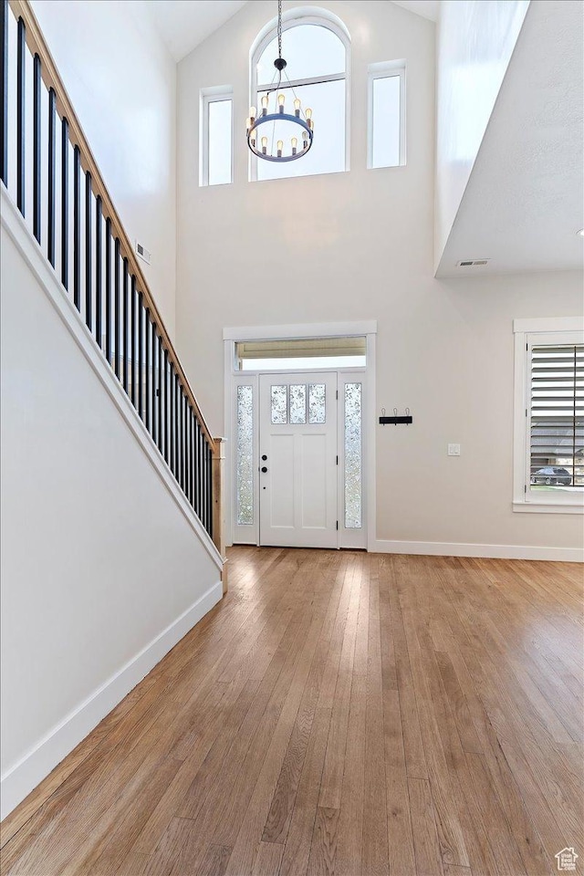 foyer featuring hardwood / wood-style floors, an inviting chandelier, baseboards, and stairway