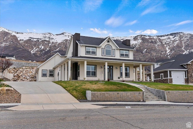 view of front of house featuring a mountain view, driveway, board and batten siding, a front lawn, and a porch