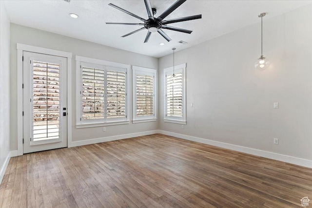 empty room with visible vents, baseboards, a ceiling fan, and wood finished floors