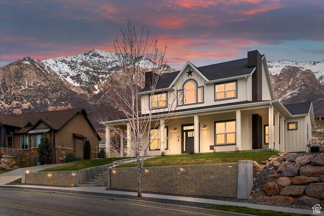 view of front of home featuring a mountain view, a chimney, covered porch, and a fenced front yard