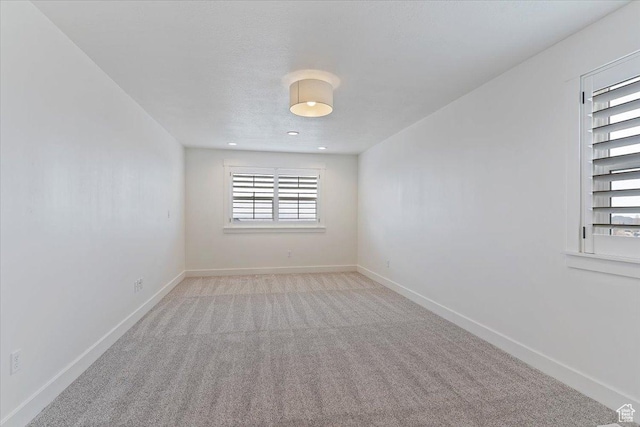 spare room featuring baseboards and light colored carpet