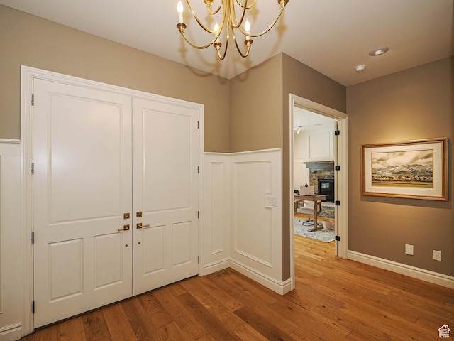 1979 E Olympus Point Dr, Holladay, UT 84117 - foyer entrance with a stone fireplace, an inviting chandelier, wainscoting, a decorative wall, and wood finished floors