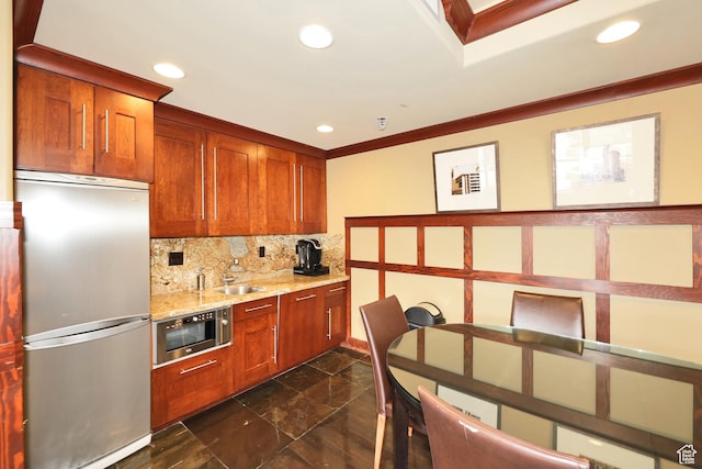 kitchen featuring tasteful backsplash, a sink, ornamental molding, stainless steel refrigerator, and built in microwave