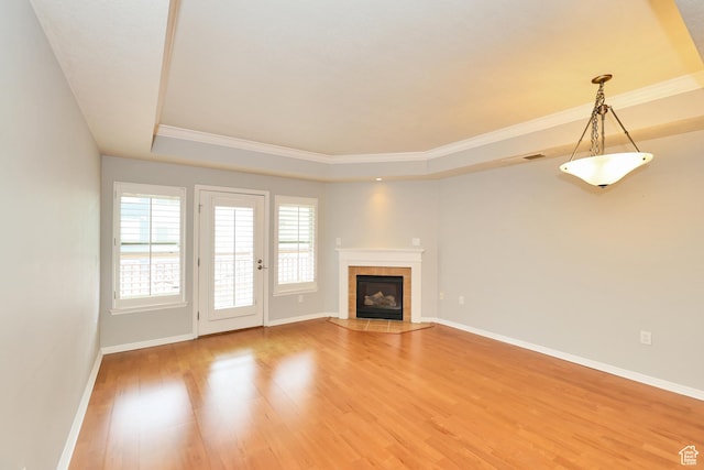 unfurnished living room with baseboards, a tiled fireplace, light wood-style floors, visible vents, and a raised ceiling
