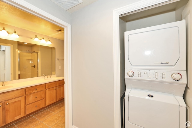 laundry area with a sink, visible vents, stacked washer / dryer, and light tile patterned floors