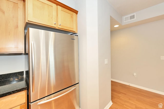 kitchen featuring baseboards, freestanding refrigerator, light wood-style floors, visible vents, and light brown cabinetry