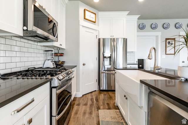 887 S 3050 W, Syracuse, UT 84075 - kitchen with stainless steel appliances, dark countertops, dark wood-type flooring, white cabinetry, and decorative backsplash