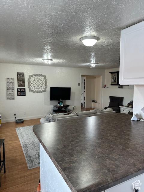 56 E Center St Unit 1, Richfield, UT 84701 - kitchen with open floor plan, dark countertops, white cabinets, dark wood-style flooring, and a textured ceiling