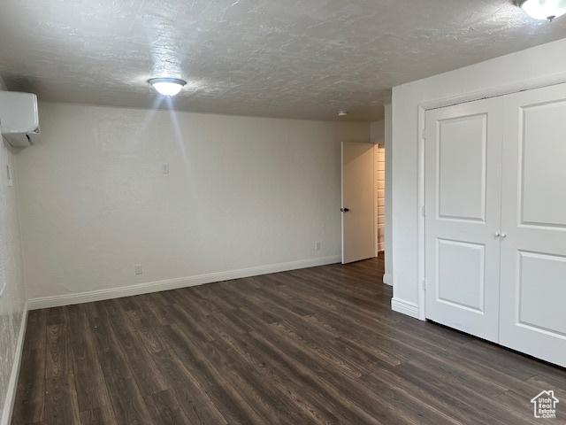 56 E Center St Unit 1, Richfield, UT 84701 - unfurnished bedroom featuring a wall mounted air conditioner, dark wood finished floors, a textured ceiling, and a closet