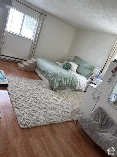 56 E Center St Unit 1, Richfield, UT 84701 - bedroom featuring a textured ceiling, wood finished floors, and a baseboard heating unit
