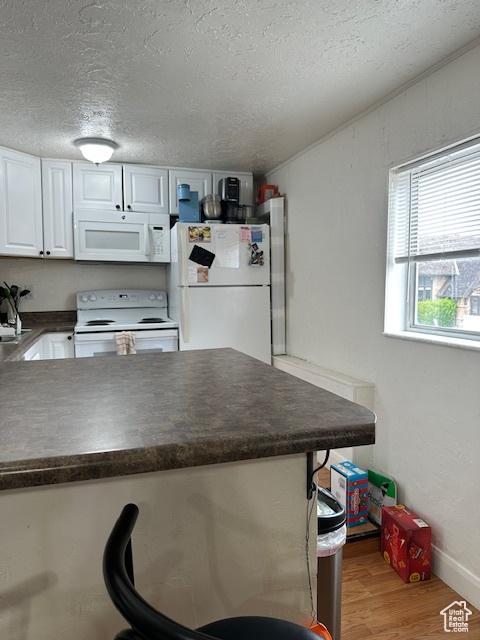 56 E Center St Unit 1, Richfield, UT 84701 - kitchen with white appliances, dark countertops, white cabinetry, a textured ceiling, and light wood-type flooring