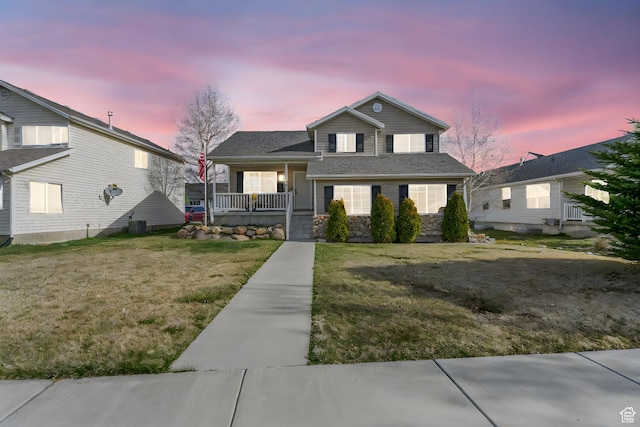 view of front of house featuring a yard, stone siding, and covered porch