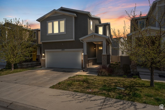 view of front of house featuring a garage, stucco siding, concrete driveway, and brick siding