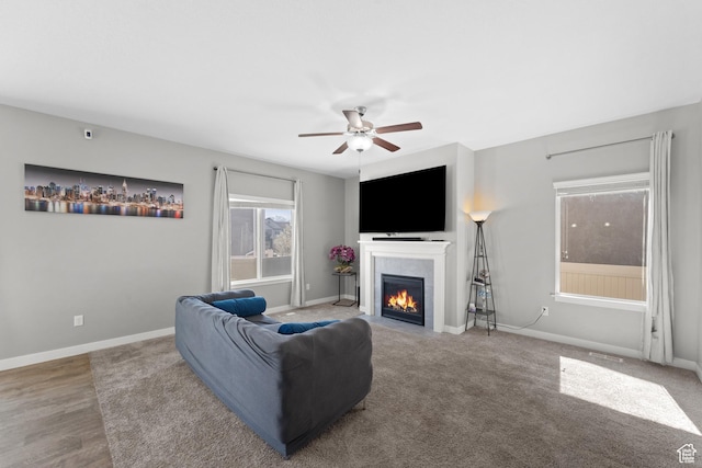 living area with a tiled fireplace, baseboards, and a ceiling fan