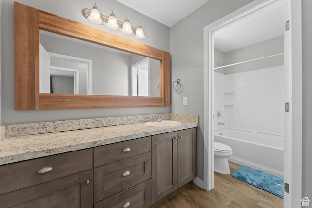 full bath featuring vanity, bathtub / shower combination, toilet, and wood finished floors