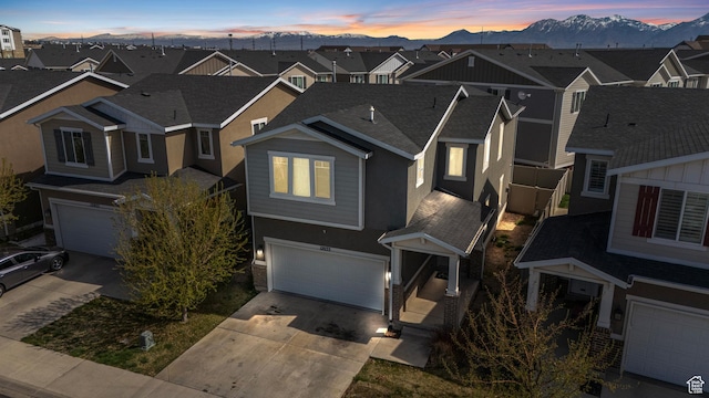 view of front of house featuring an attached garage, a mountain view, concrete driveway, and a residential view