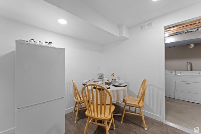 dining room featuring separate washer and dryer, wood finished floors, baseboards, and visible vents