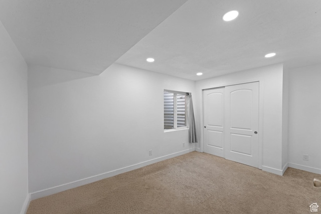 interior space with a closet, light colored carpet, baseboards, and recessed lighting
