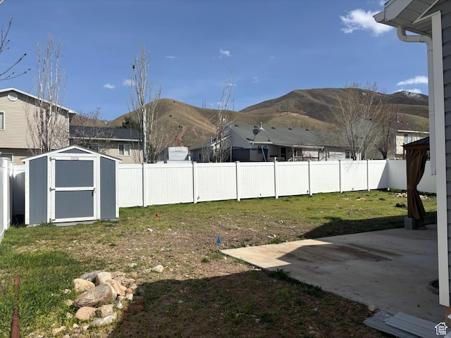 1081 S 900 W, Tooele, UT 84074 - view of yard featuring an outdoor structure, a mountain view, a patio area, a storage shed, and a fenced backyard