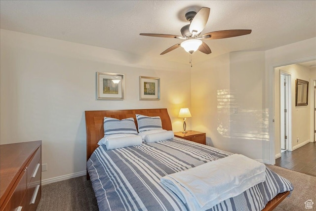 bedroom with a textured ceiling, wood finished floors, ceiling fan, and baseboards