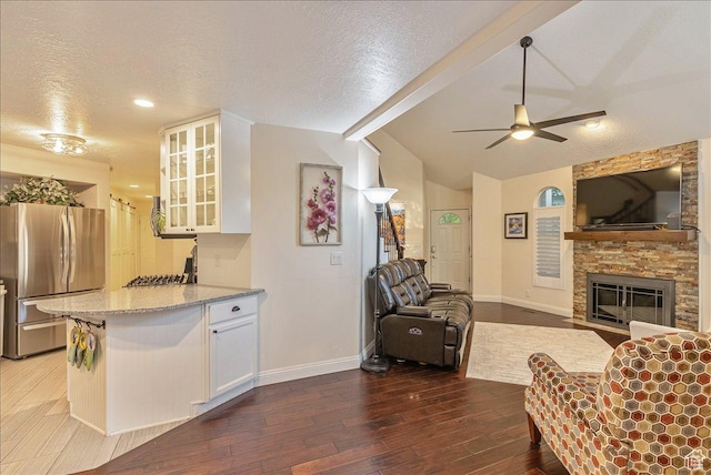 kitchen featuring freestanding refrigerator, a textured ceiling, white cabinets, vaulted ceiling with beams, and wood-type flooring