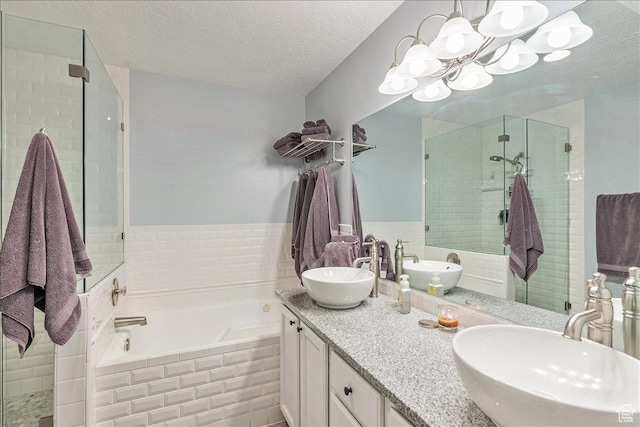 full bath featuring a sink, a shower stall, and a textured ceiling
