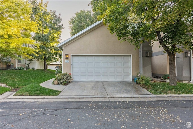 view of front facade with concrete driveway, a front yard, stucco siding, and a garage