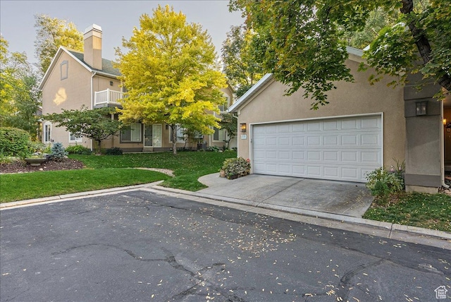 view of front facade with concrete driveway, a front lawn, and stucco siding