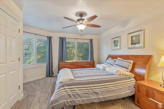 carpeted bedroom featuring baseboards, a textured ceiling, and a ceiling fan