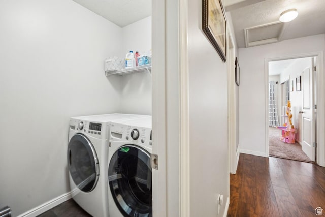 clothes washing area featuring independent washer and dryer, dark wood-type flooring, laundry area, and baseboards