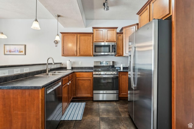 kitchen featuring brown cabinetry, a peninsula, dark countertops, a sink, and stainless steel appliances