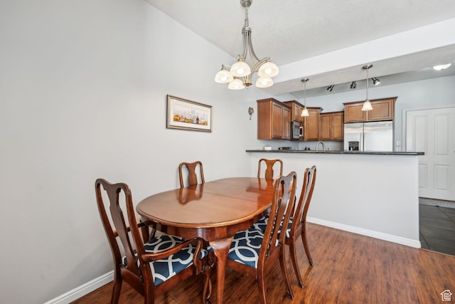 dining space featuring dark wood-type flooring, an inviting chandelier, baseboards, and vaulted ceiling