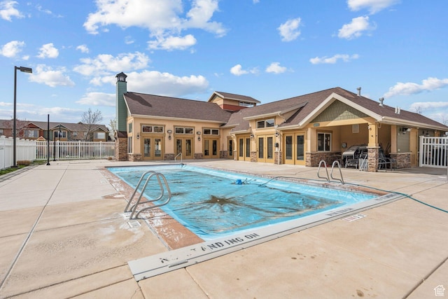 pool featuring french doors, a patio area, and fence