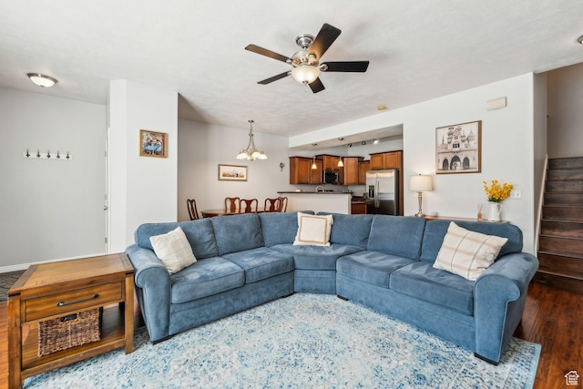 living area featuring ceiling fan with notable chandelier, wood finished floors, and stairs