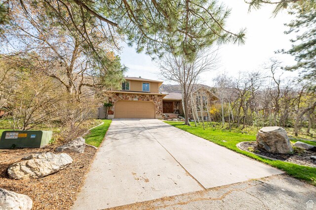2406 Woodland Dr, Ogden, UT 84403 - view of front of house featuring a garage, stucco siding, stone siding, a front lawn, and driveway
