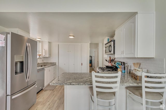 1224 S 760 W, Provo, UT 84601 - kitchen with a peninsula, white cabinets, decorative backsplash, stainless steel appliances, and a sink