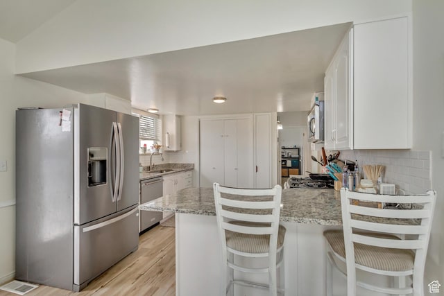 1224 S 760 W, Provo, UT 84601 - kitchen featuring a peninsula, white cabinetry, decorative backsplash, stainless steel appliances, and a sink