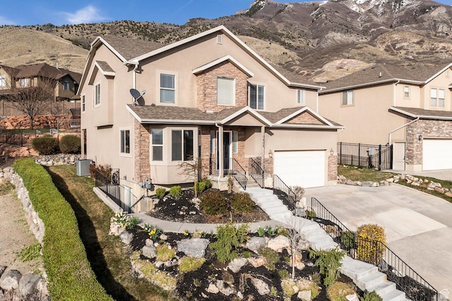 traditional-style house featuring stucco siding, stone siding, concrete driveway, and fence