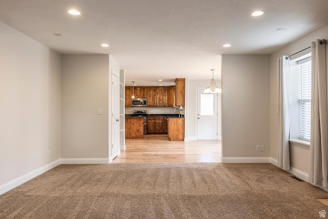 unfurnished living room with light carpet, recessed lighting, healthy amount of natural light, and baseboards