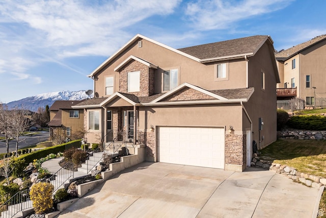 traditional home featuring stucco siding, concrete driveway, stone siding, a garage, and a mountain view